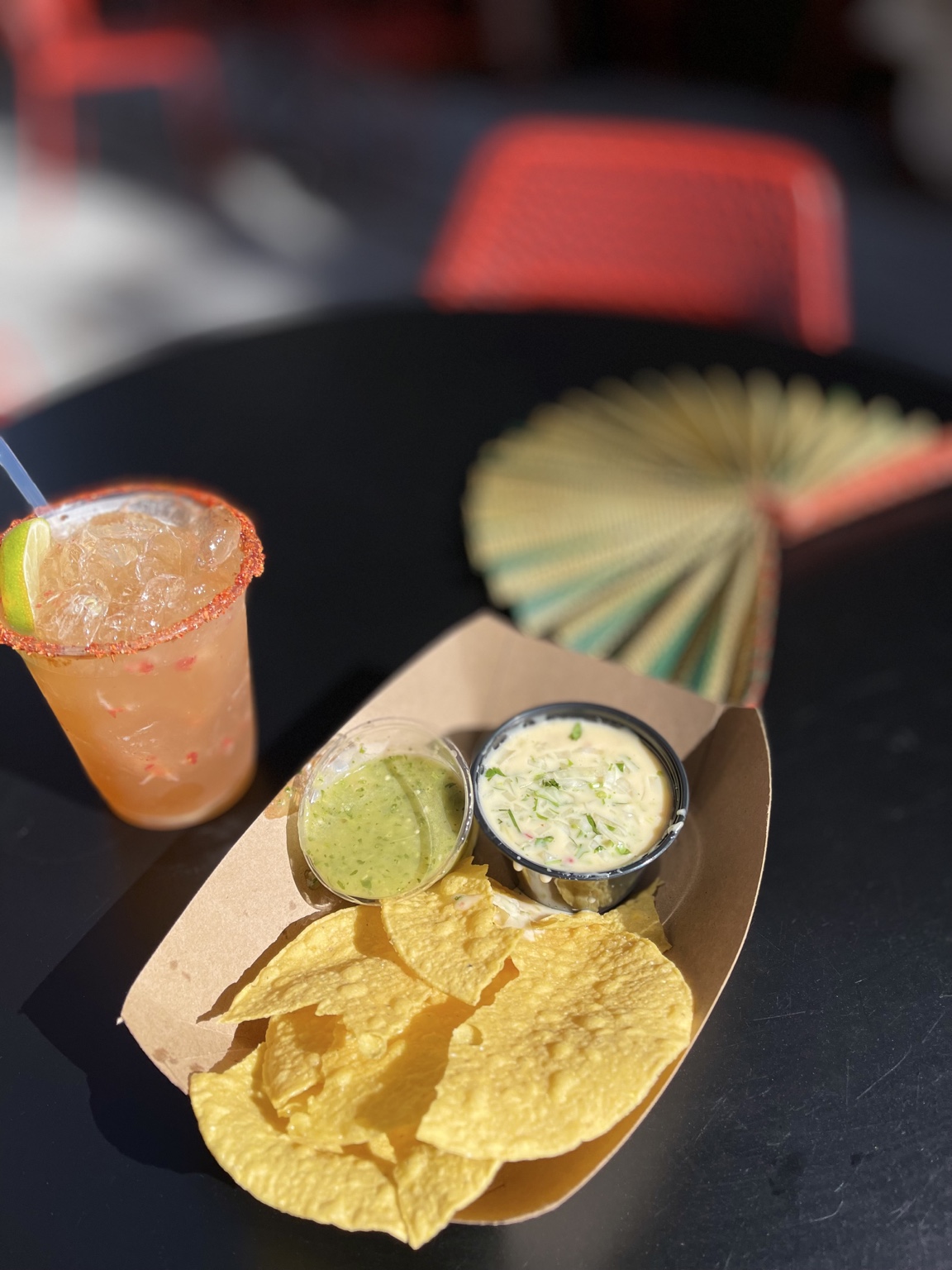 Chips, dips, and a drink on a table.
