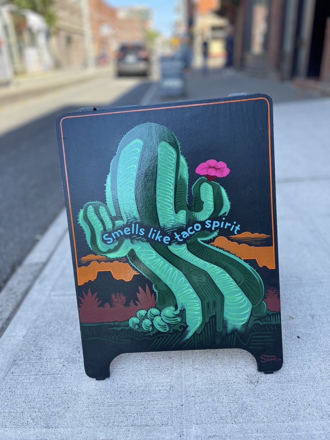 A colorful sidewalk sign for tacos.